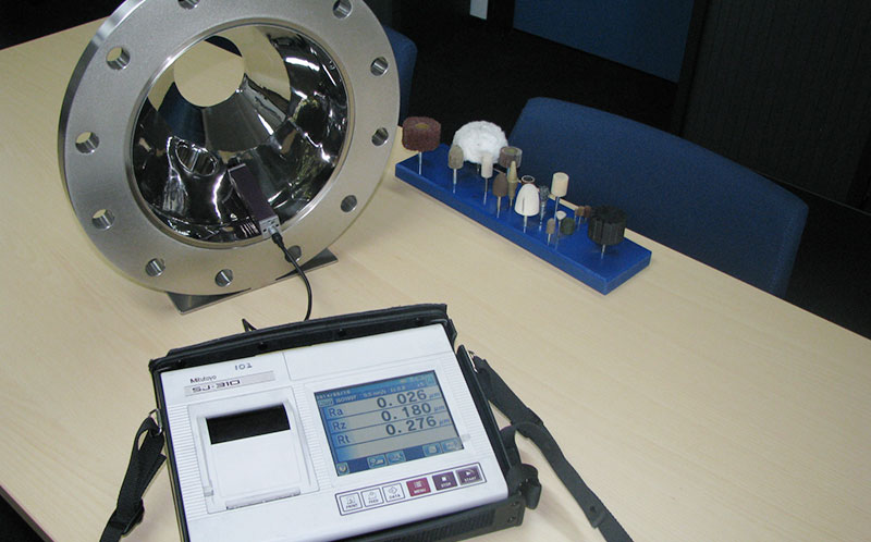 Measuring the Ra value of a composite part using a roughness tester or Ra meter.